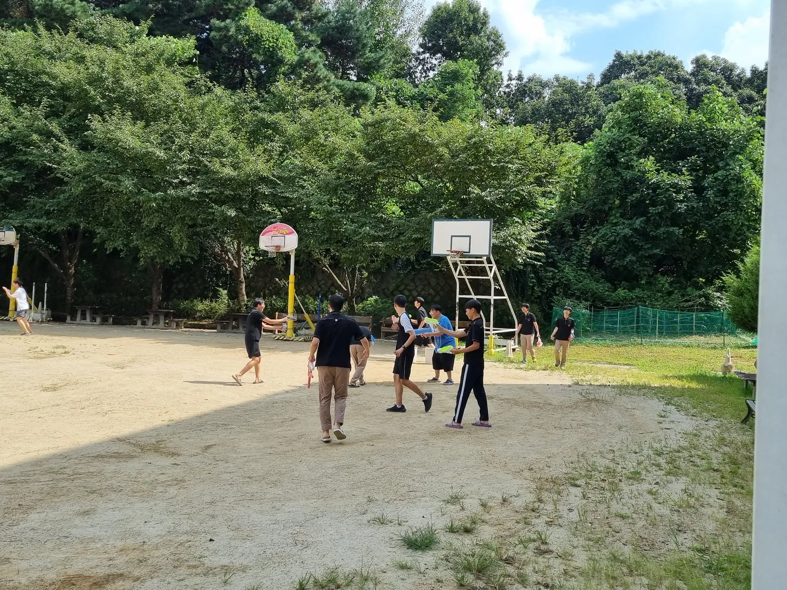 학교 농구장에서 물총 놀이를 하는 학생과 교사