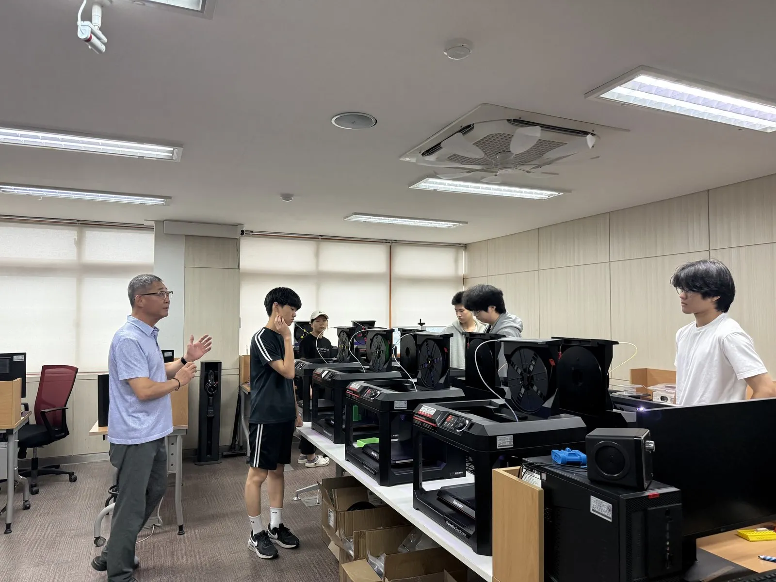 3D 프린터 앞에서 강사의 설명을 듣는 학생들