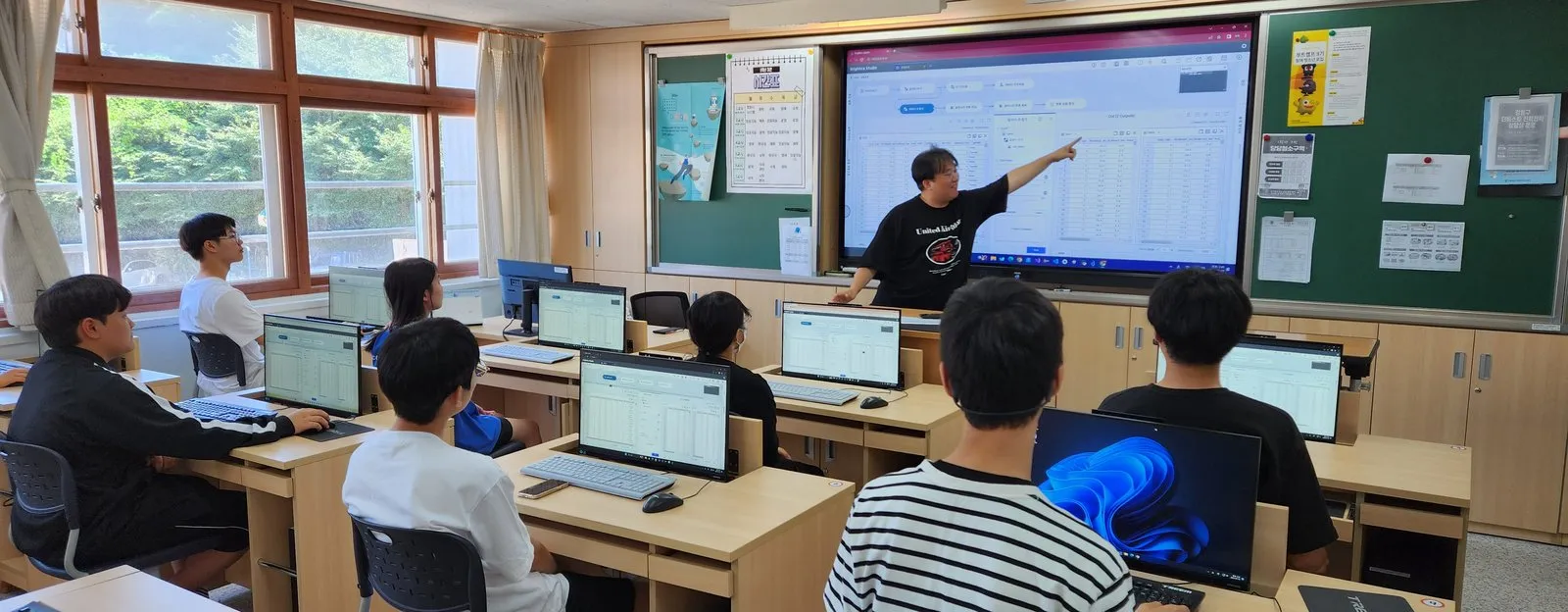 교실에서 강사가 화면의 데이터 분석 흐름을 가리키며 설명하는 장면