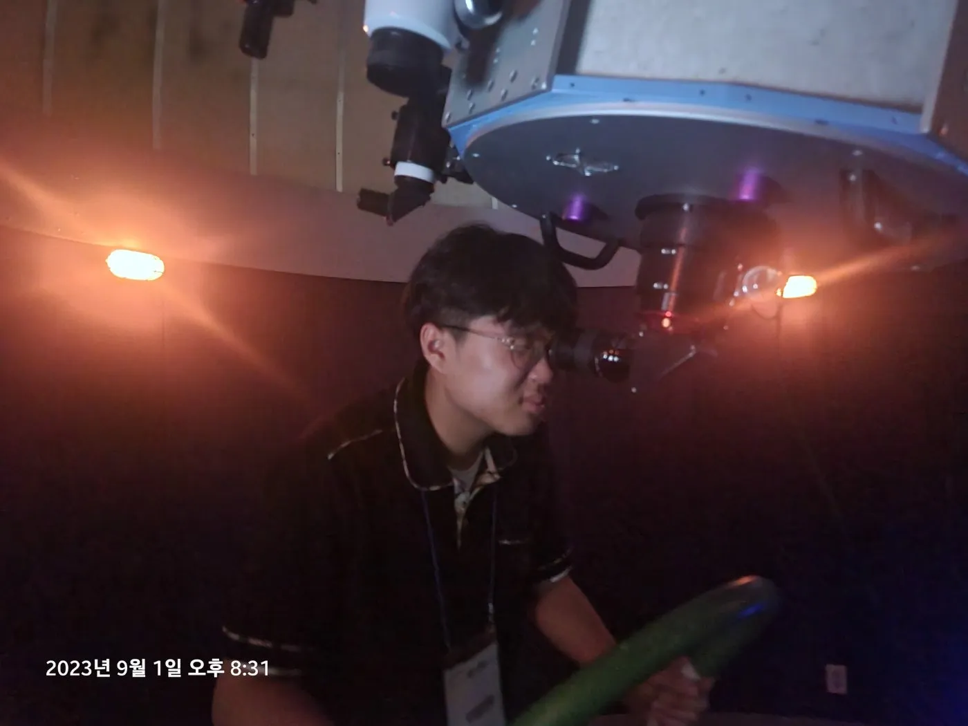 천문대 돔 안에서 망원경 접안렌즈를 들여다보는 학생