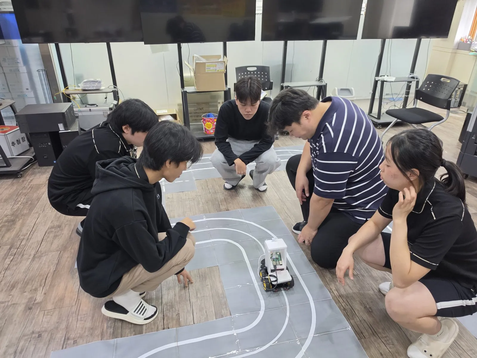 교사와 함께 자동차의 동작을 점검하는 팀