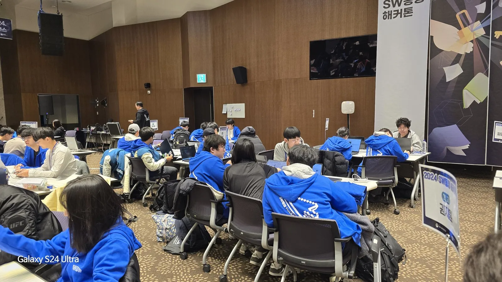 해커톤 행사장 전경. 참가 팀들이 원탁마다 앉아 작업하고 있다