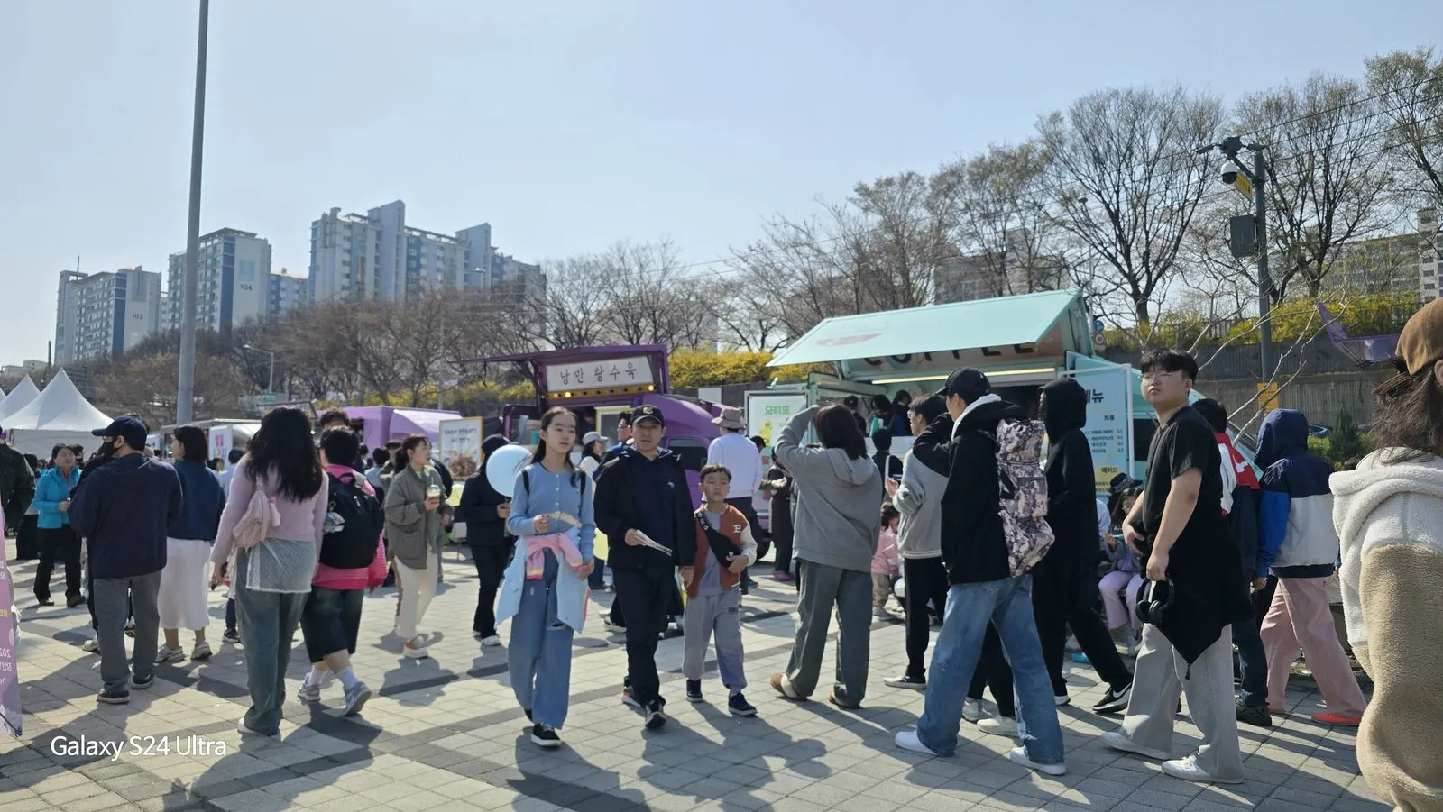 축제 부스가 늘어선 공원을 걷는 사람들