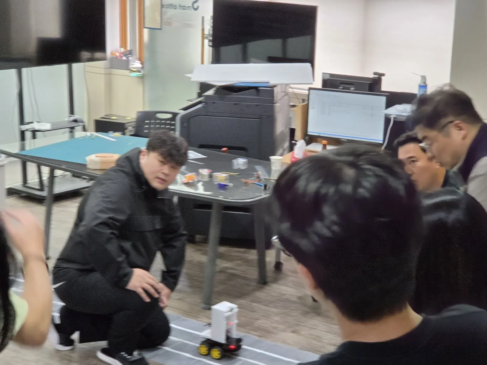 모형 자동차 옆에서 동작을 설명하는 모습