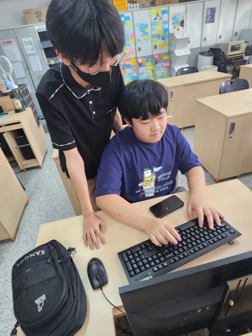 인공지능소프트웨어과 재학생이 중학생의 실습을 돕는 장면