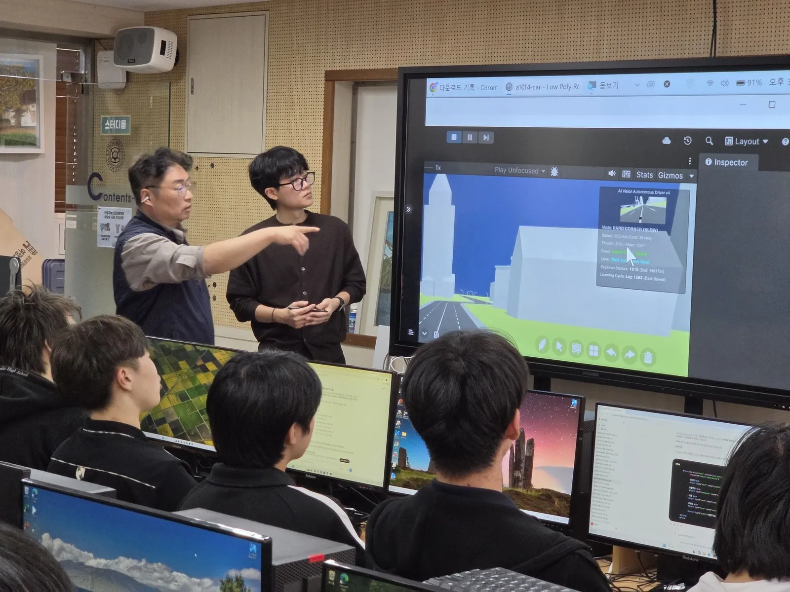 교실 화면 앞에서 실습 내용을 설명하는 학생과 교사