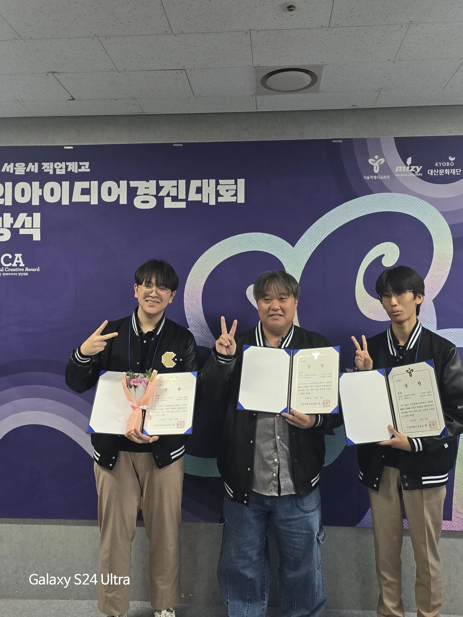 제19회 서울시 직업계고 창의아이디어경진대회 시상식에서 상장을 든 학생 2명과 지도교사